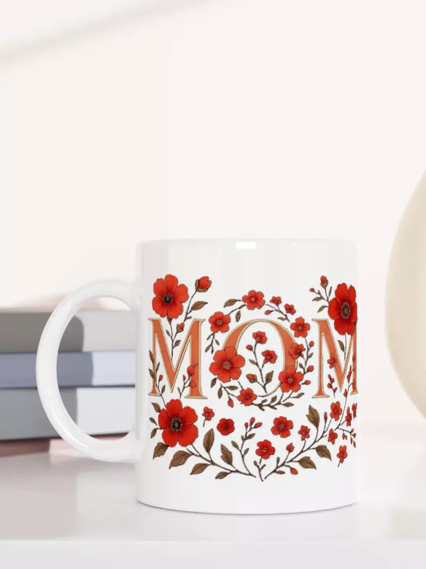 Weiße Keramiktasse mit floralem Blumenkranz und Schriftzug MOM in Rot, glänzende Oberfläche, liebevolle Geschenkidee für Muttertag oder Alltag