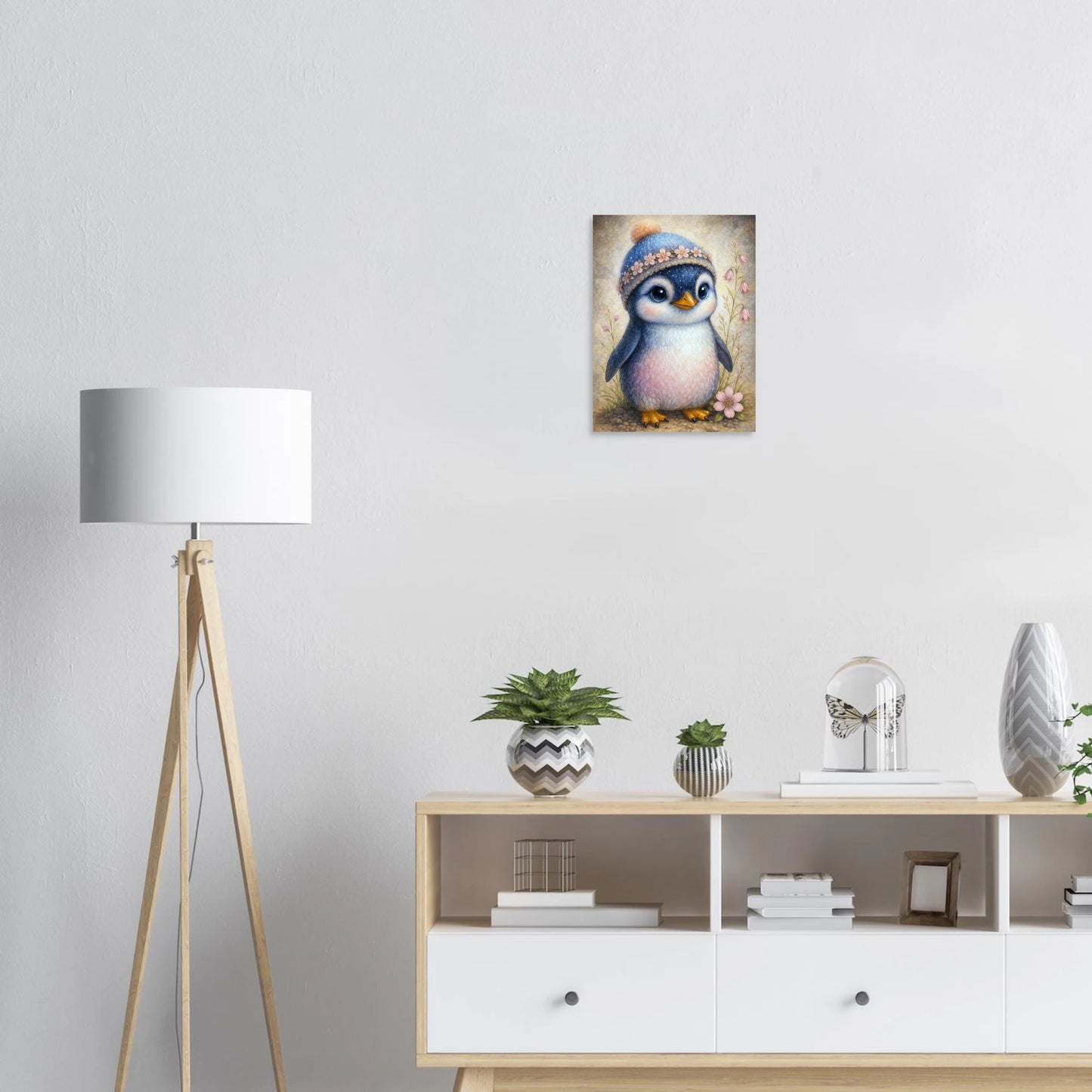 Süßer Baby-Pinguin mit gestrickter Mütze und Blütenband in Pastellfarben, zarte Blumen am Rand, Kinderzimmer-Motiv.